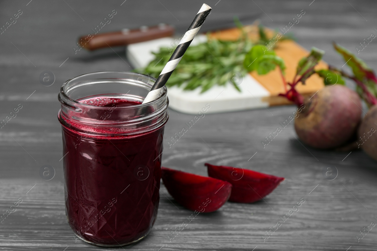 Photo of Fresh beet juice and raw vegetable on grey wooden table. Space for text