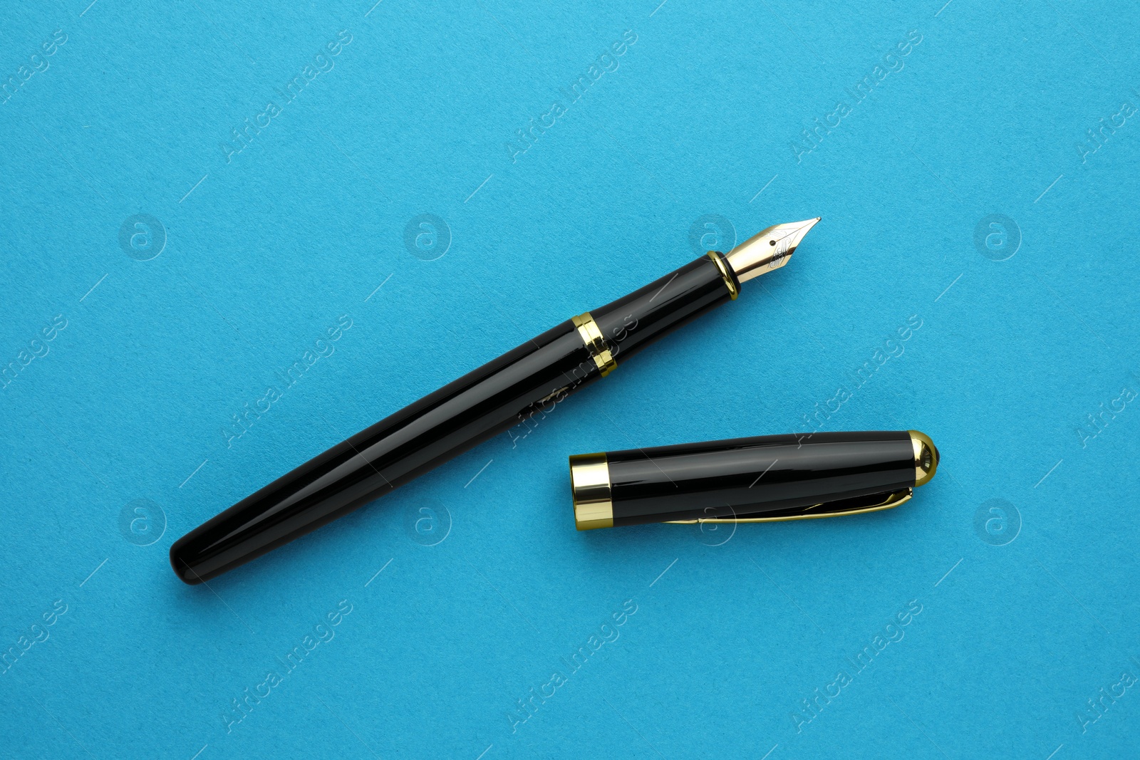 Photo of Stylish fountain pen with cap on light blue background, flat lay