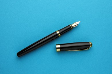 Stylish fountain pen with cap on light blue background, flat lay