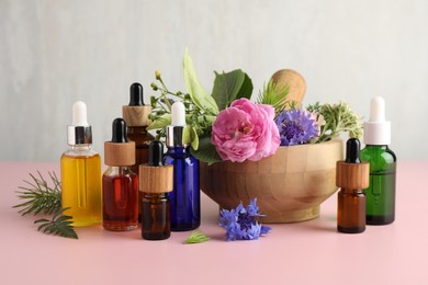 Photo of Aromatherapy. Different essential oils and flowers on pink table