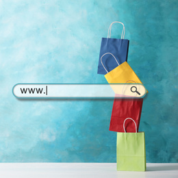 Image of Online shopping. Search bar and colorful paper bags on background