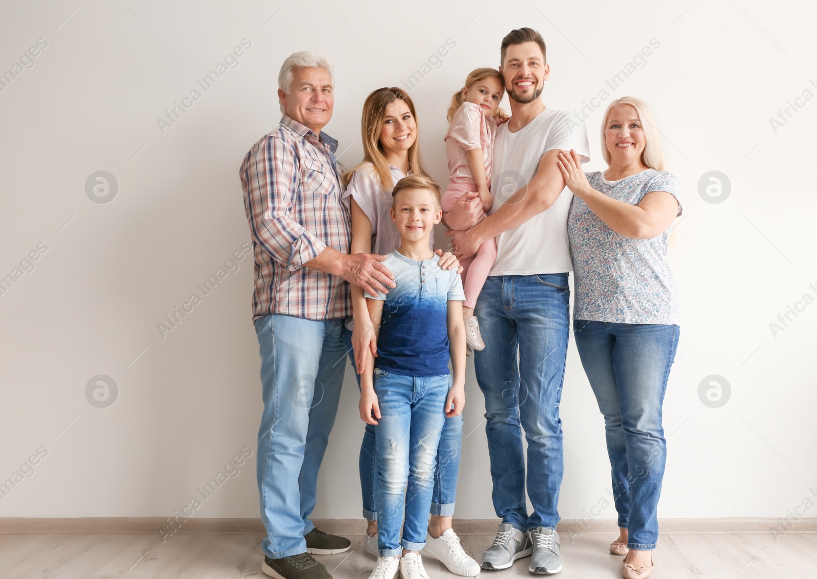 Photo of Happy family with cute kids near light wall