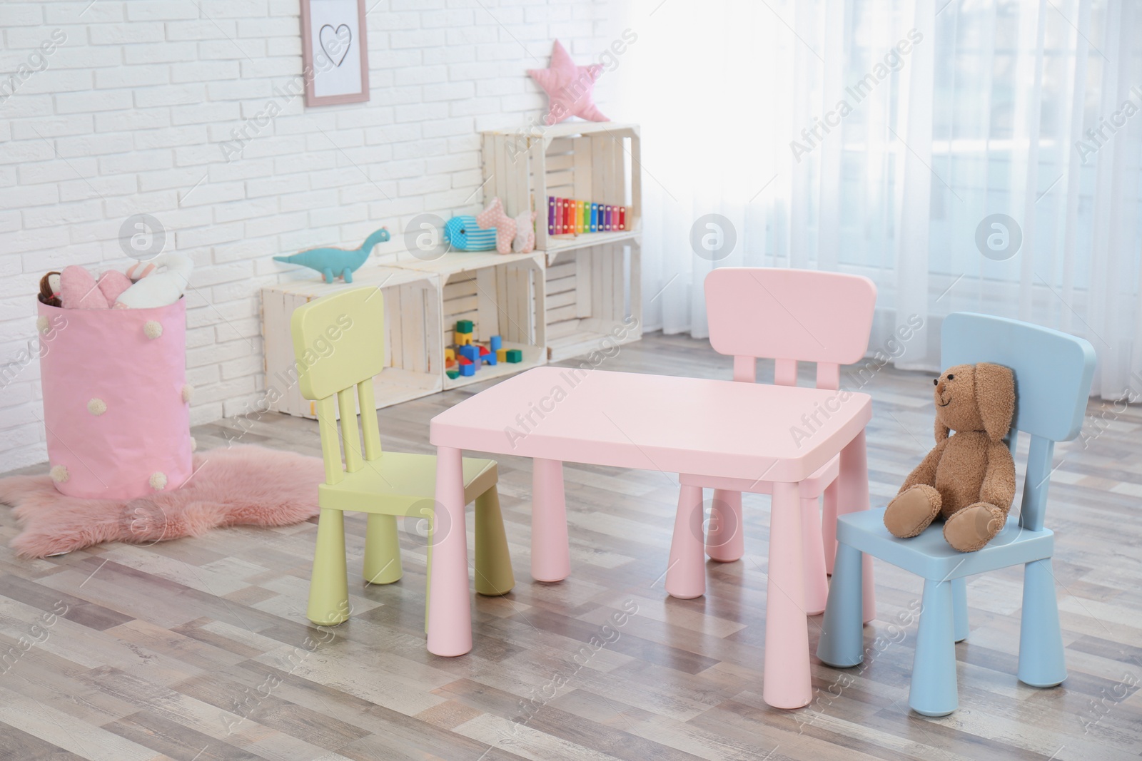 Photo of Cozy kids room interior with table, chairs and toys