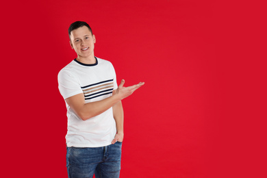 Photo of Happy handsome young man on red background. Space for text