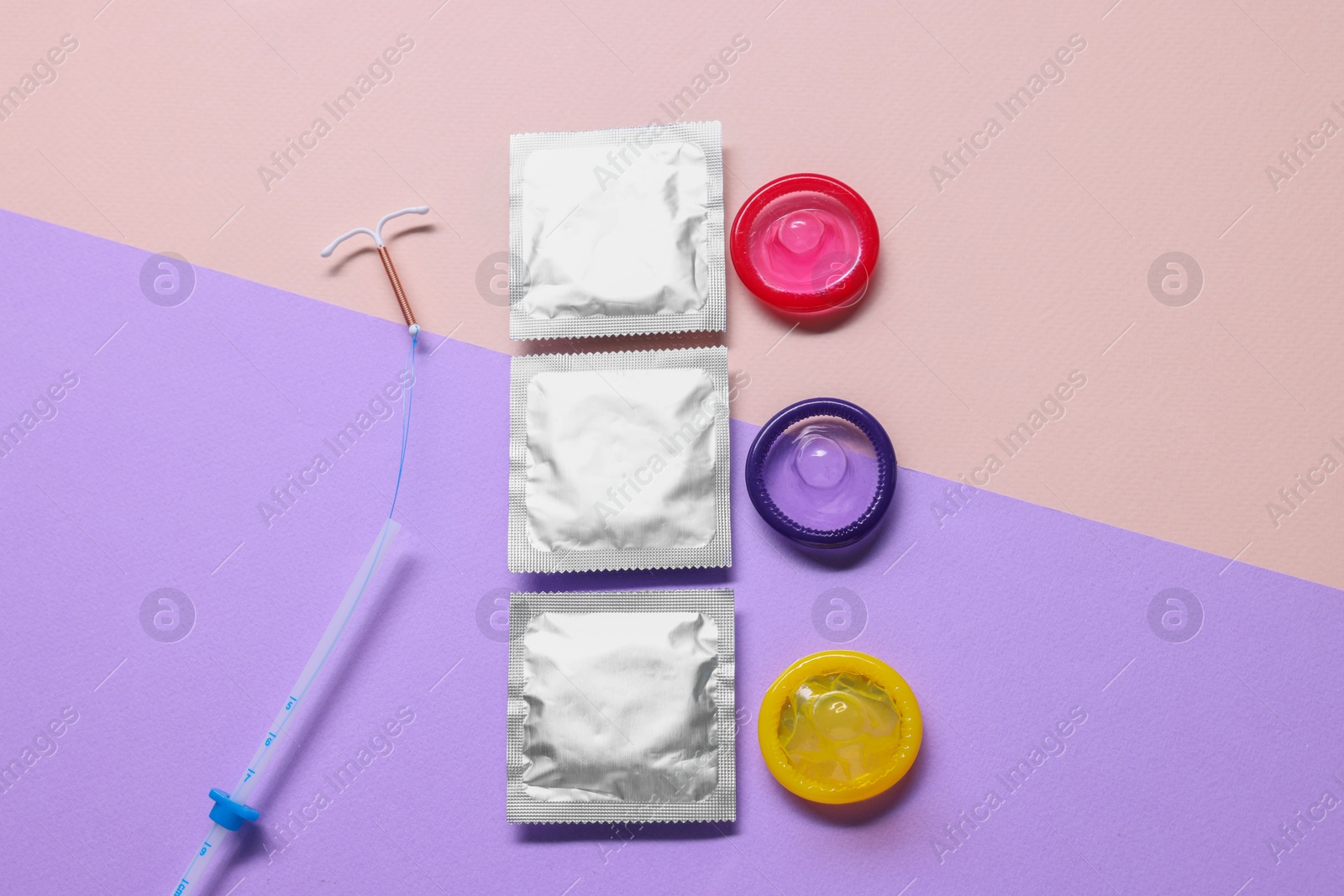 Photo of Condoms and intrauterine device on color background, flat lay. Choosing method of contraception