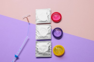 Photo of Condoms and intrauterine device on color background, flat lay. Choosing method of contraception