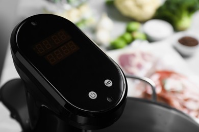 Photo of Sous vide cooker in pot on table, closeup. Thermal immersion circulator