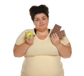 Photo of Emotional overweight woman with apple and chocolate on white background