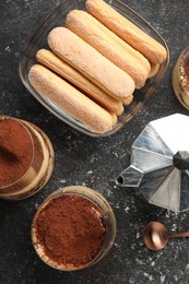 Photo of Delicious tiramisu in glasses and ingredients on grey textured table, flat lay