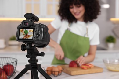 Food blogger cooking while recording video in kitchen, focus on camera