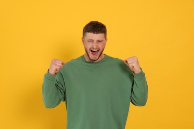 Photo of Aggressive young man shouting on orange background