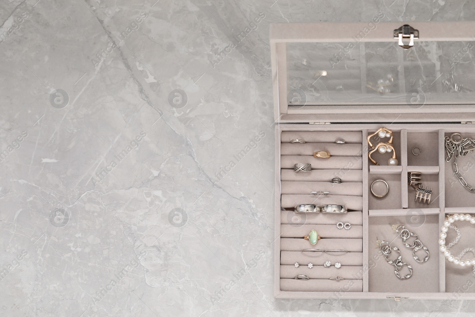 Photo of Jewelry box with many different accessories on light grey table, top view. Space for text