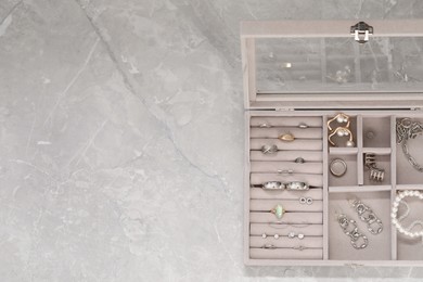 Photo of Jewelry box with many different accessories on light grey table, top view. Space for text