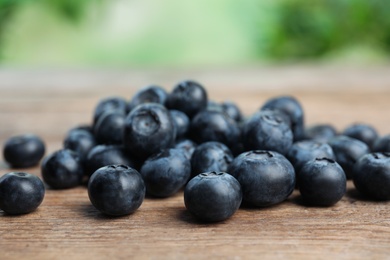 Photo of Pile of tasty fresh blueberries on wooden table, closeup