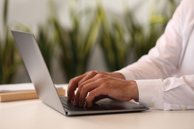 Photo of Man using modern laptop at desk in office, closeup