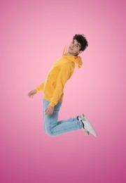 Teenage boy jumping on pink background, full length portrait