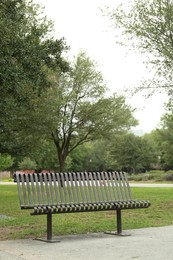 Stylish metal bench in park on sunny day