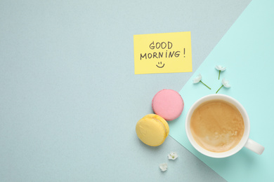 Photo of Delicious coffee, macarons, flowers and card with GOOD MORNING wish on color background, flat lay. Space for text