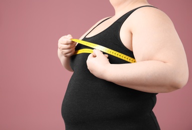 Photo of Overweight woman with measuring tape on color background