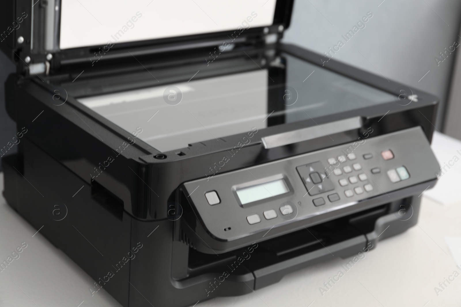 Photo of Open modern printer with control panel on white table, closeup