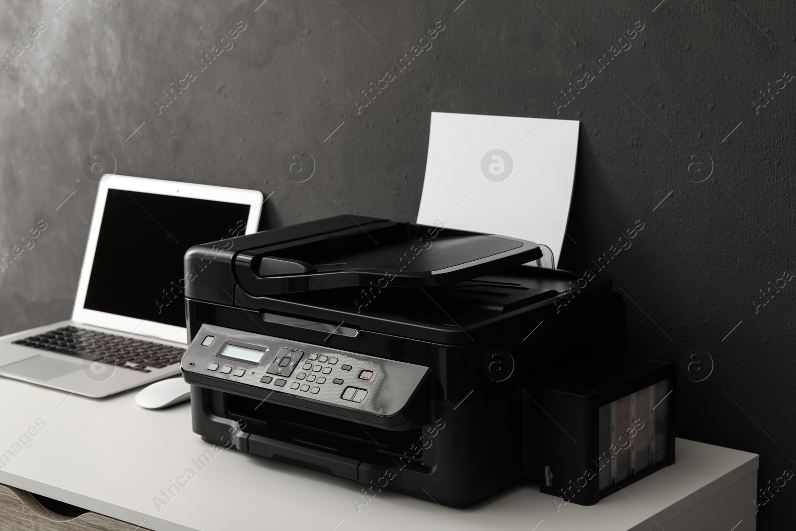Photo of New modern printer and laptop on white table