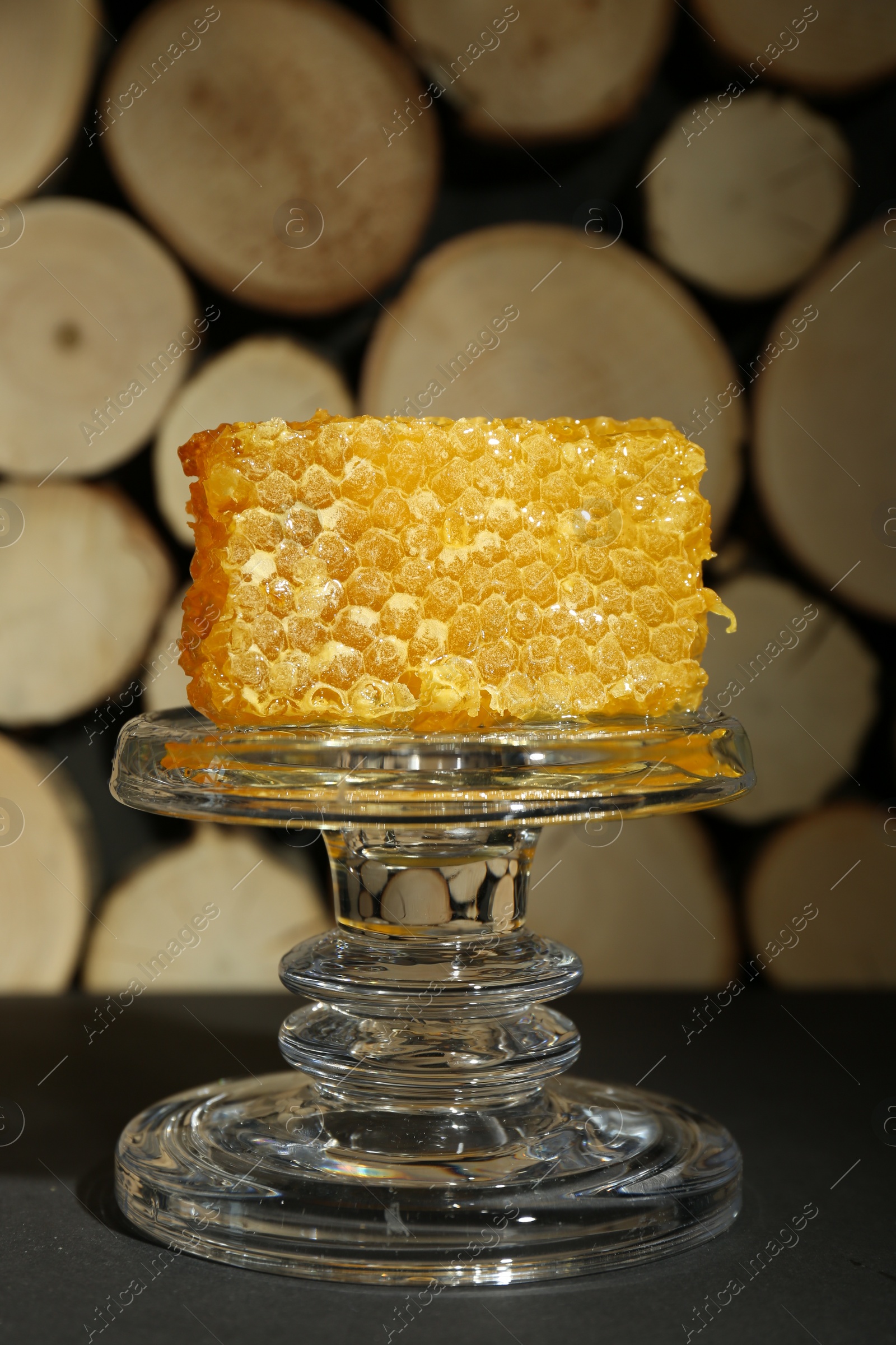 Photo of Glass stand with natural honeycomb on black table