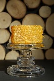 Photo of Glass stand with natural honeycomb on black table