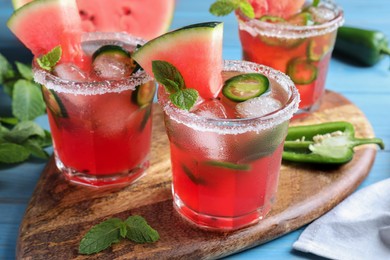 Glasses of spicy cocktail with jalapeno and mint on light blue table