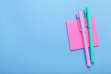 Photo of Paper notes and colorful markers on light blue background, top view. Space for text