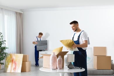 Moving service employees packaging belongings in room