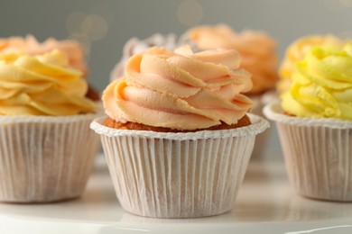Photo of Tasty cupcakes on white table against blurred lights, closeup