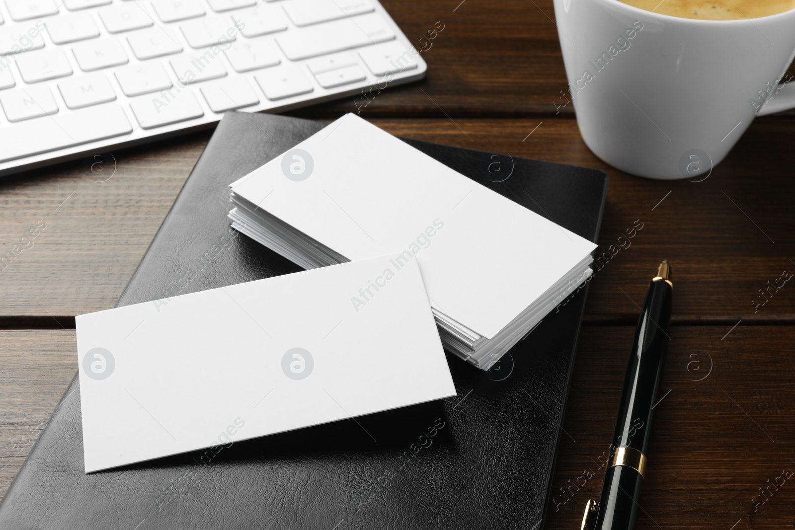 Photo of Blank business cards, notebook and pen on wooden table, closeup. Mockup for design