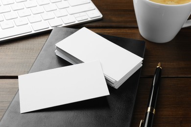 Blank business cards, notebook and pen on wooden table, closeup. Mockup for design