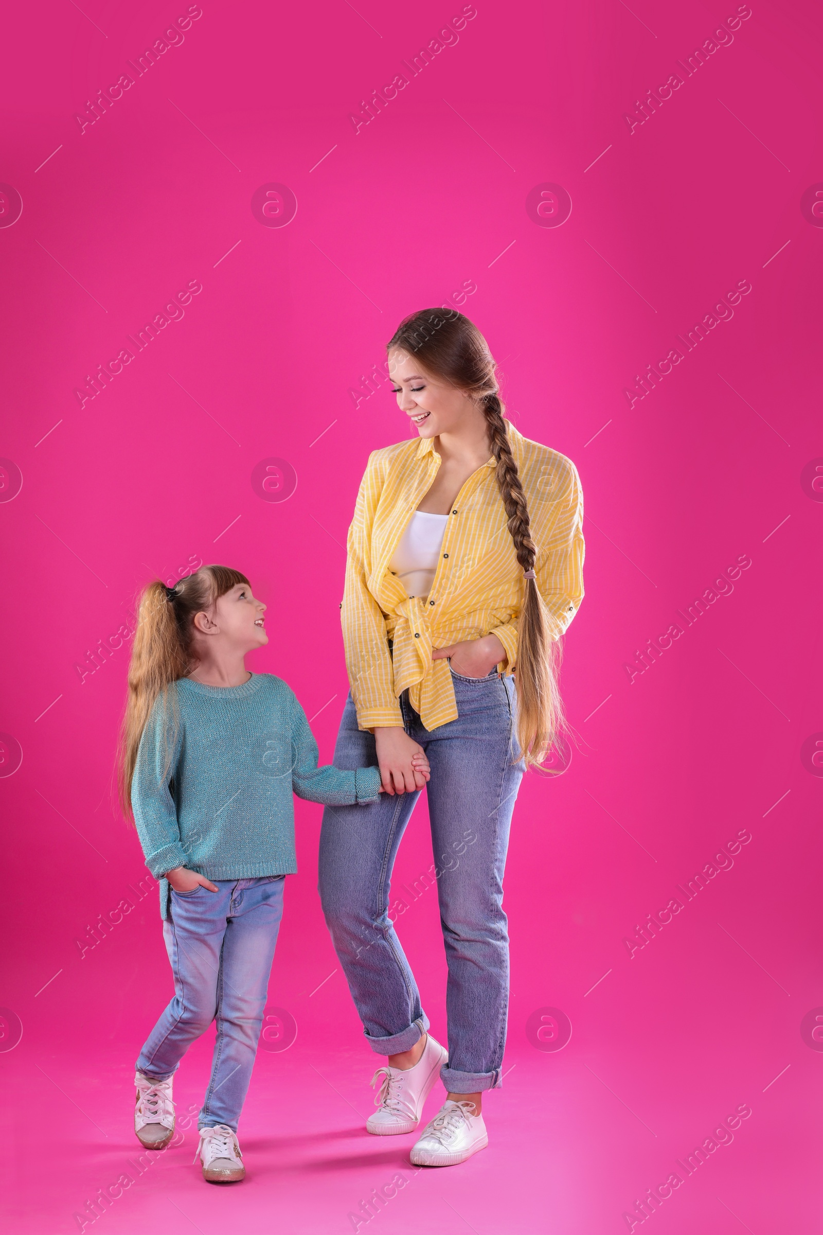 Photo of Happy woman and daughter in stylish clothes on color background