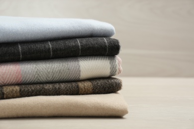 Stack of cashmere clothes on wooden table, closeup