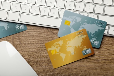 Credit cards, computer keyboard and mouse on wooden background, flat lay