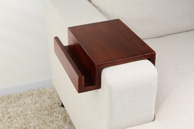 Photo of Wooden armrest table on sofa in room. Interior element