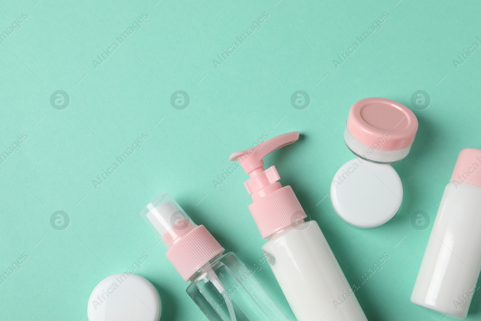 Photo of Cosmetic travel kit on turquoise background, flat lay. Space for text