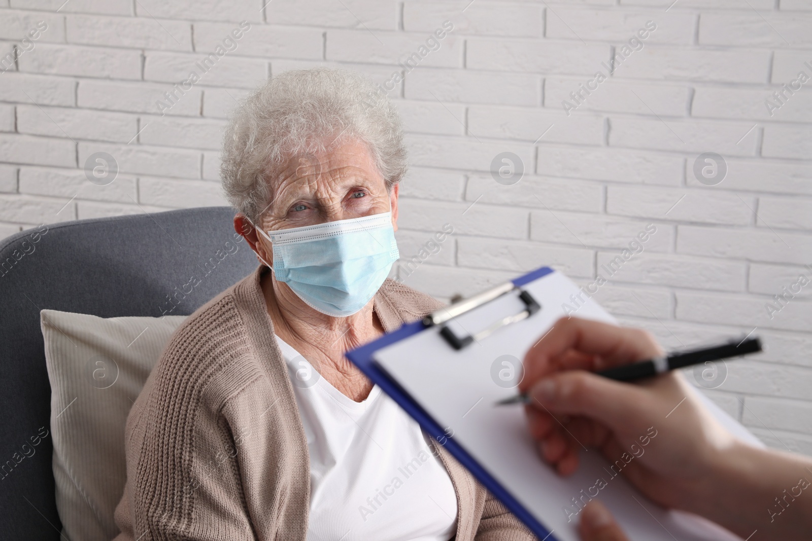 Photo of Doctor examining senior woman with protective mask at nursing home