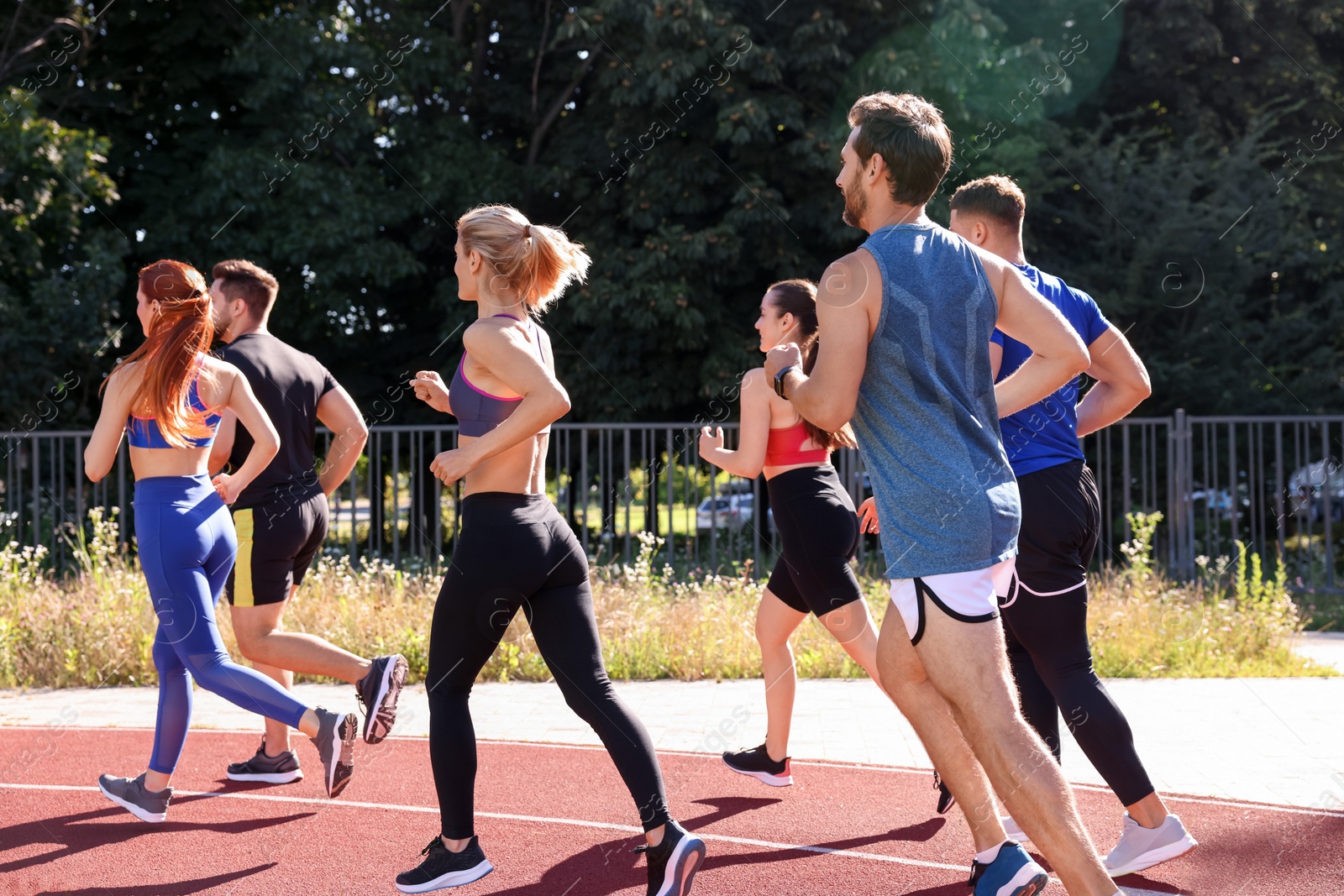 Photo of Group of people running at stadium on sunny day