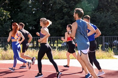 Photo of Group of people running at stadium on sunny day