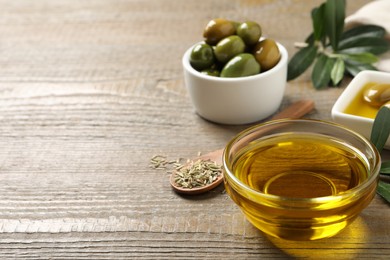 Photo of Fresh oil, ripe olives, dried herb and green leaves on wooden table. Space for text