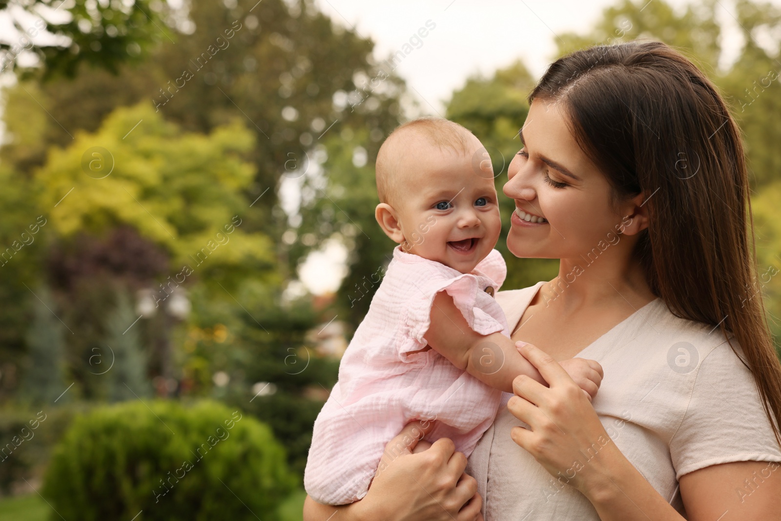 Photo of Happy mother with adorable baby walking in park on sunny day, space for text