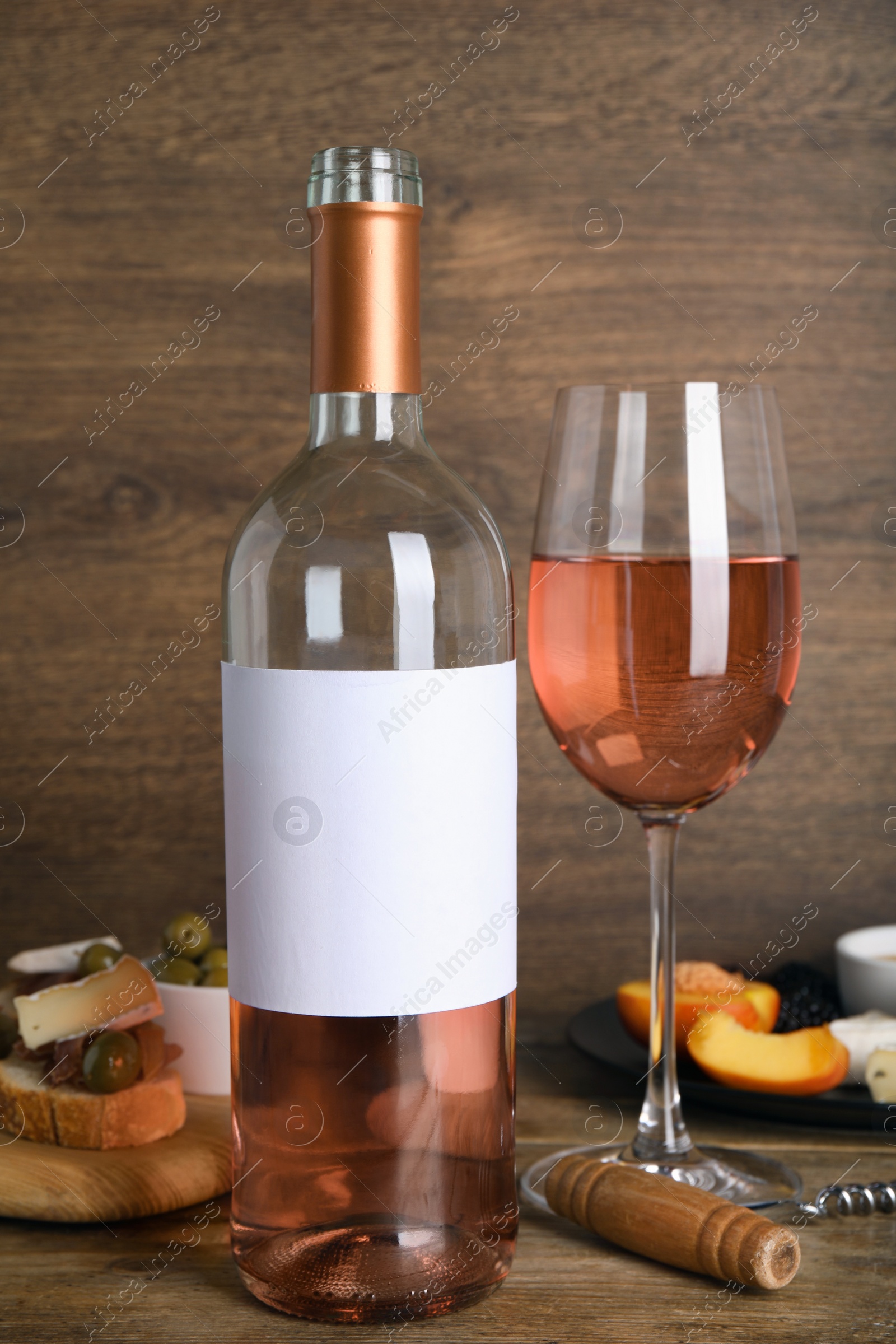 Photo of Delicious rose wine and snacks on wooden table