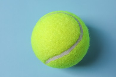 Photo of One tennis ball on light blue background, top view