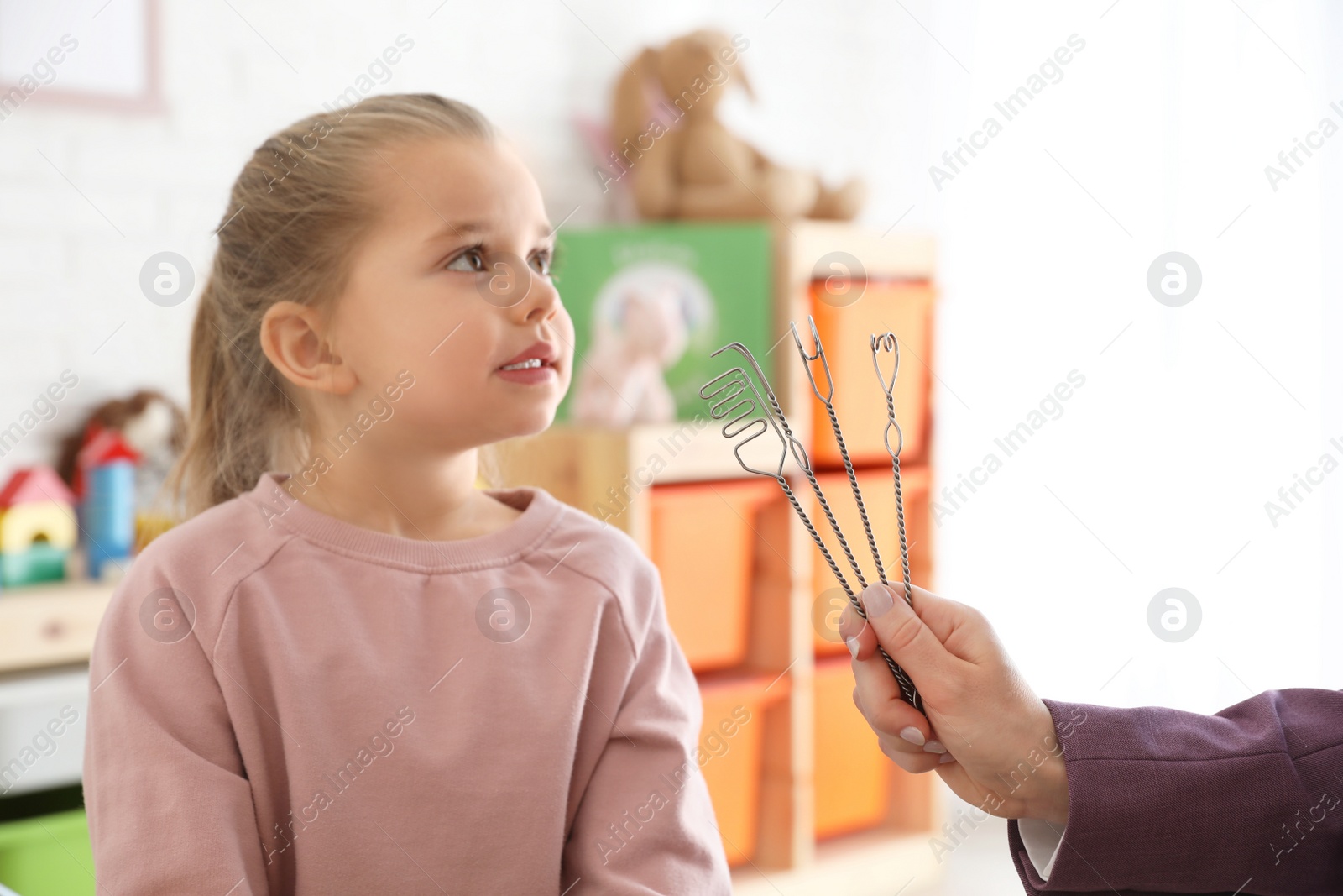 Photo of Speech therapist using logopedic probes on session with little girl in office