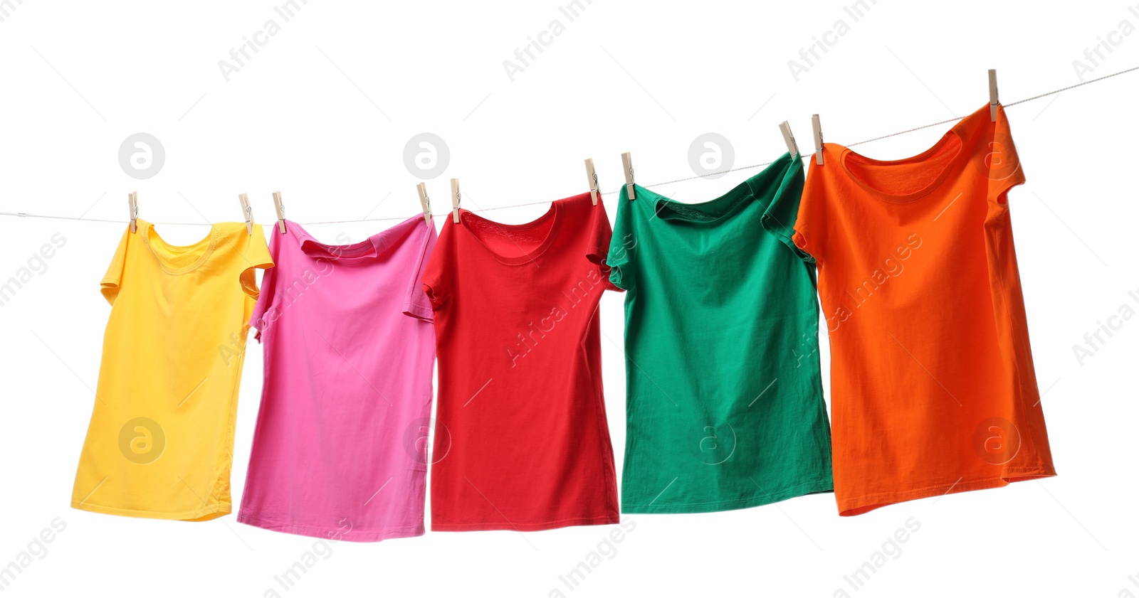 Photo of Different bright t-shirts drying on washing line against white background