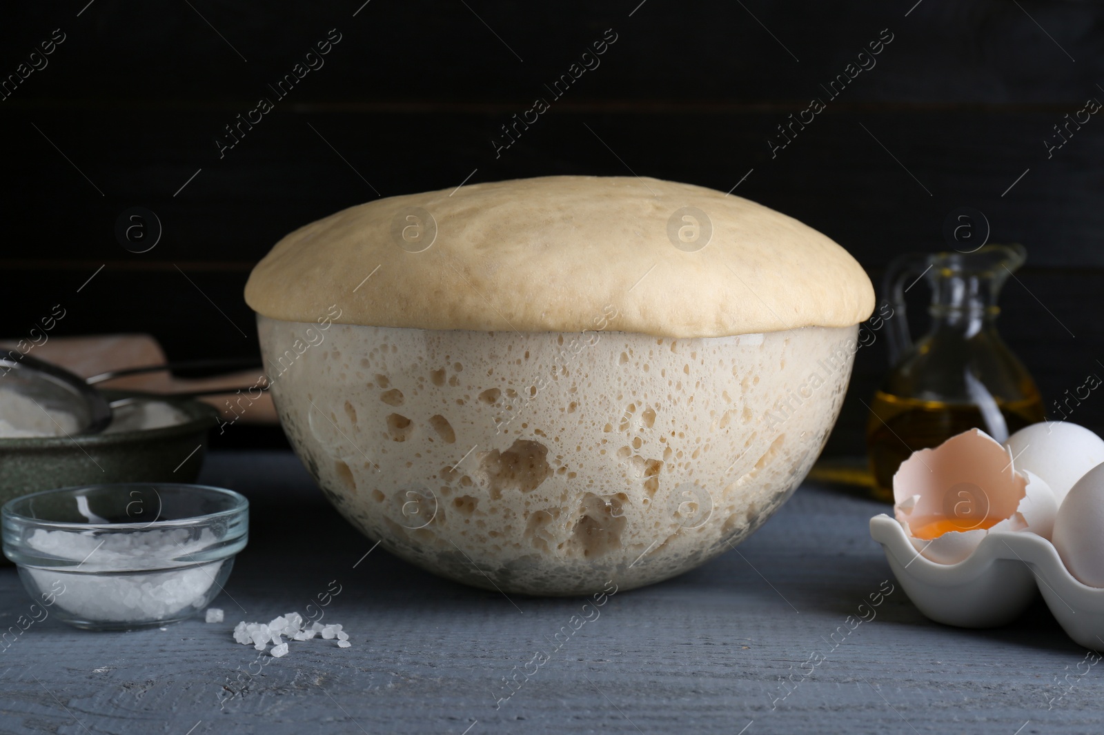 Photo of Fresh yeast dough and ingredients on grey wooden table