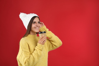 Photo of Happy beautiful woman with paper cup of mulled wine on red background. Space for text