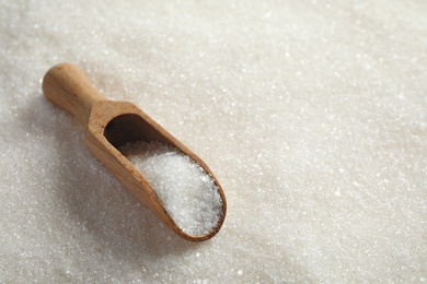 Photo of Granulated sugar and wooden scoop. Space for text